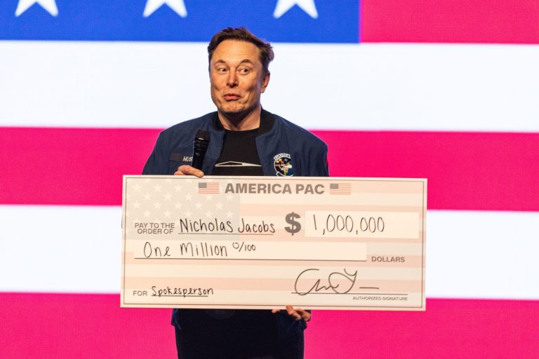 Elon Musk holds up a check during a town hall Sunday, March 30, 2025, in Green Bay, Wis. (AP Photo/Jeffrey Phelps)