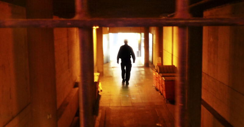 View through barred window of man walking away down corridor